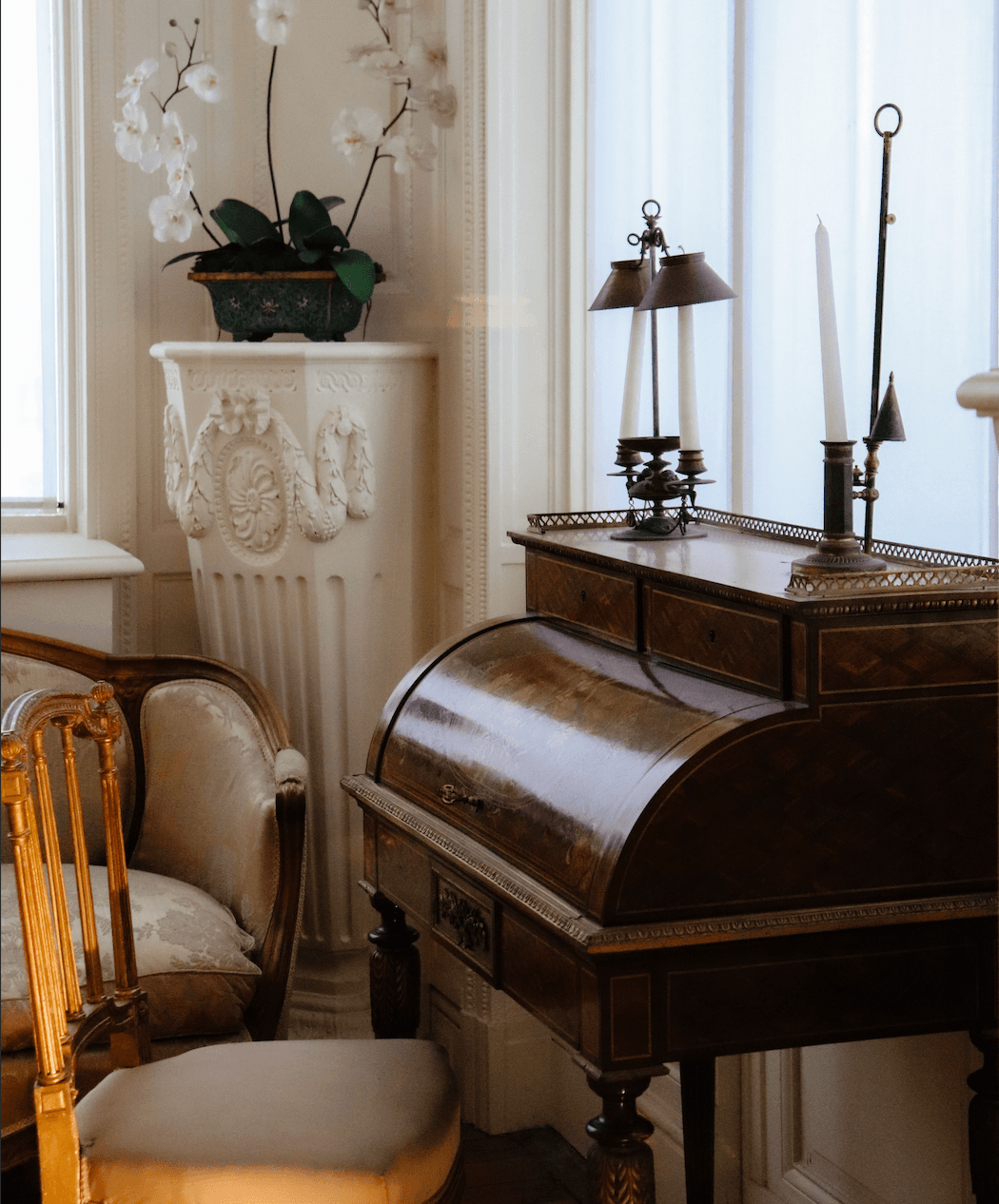 A vintage wooden writing desk paired with a period lamp